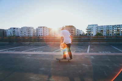 黄金时段，一名男子在建筑物附近的停车场玩滑板